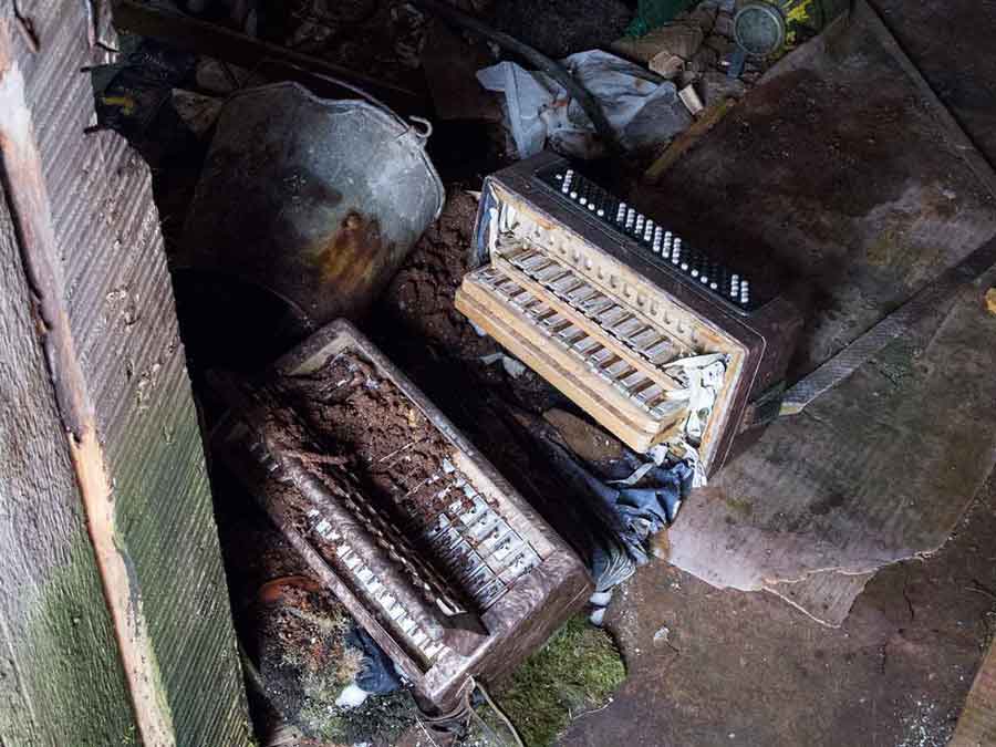 Old Soviet-made accordion on the floor of an abandoned log home near Oslyanka Mountain in the Urals of Russia.