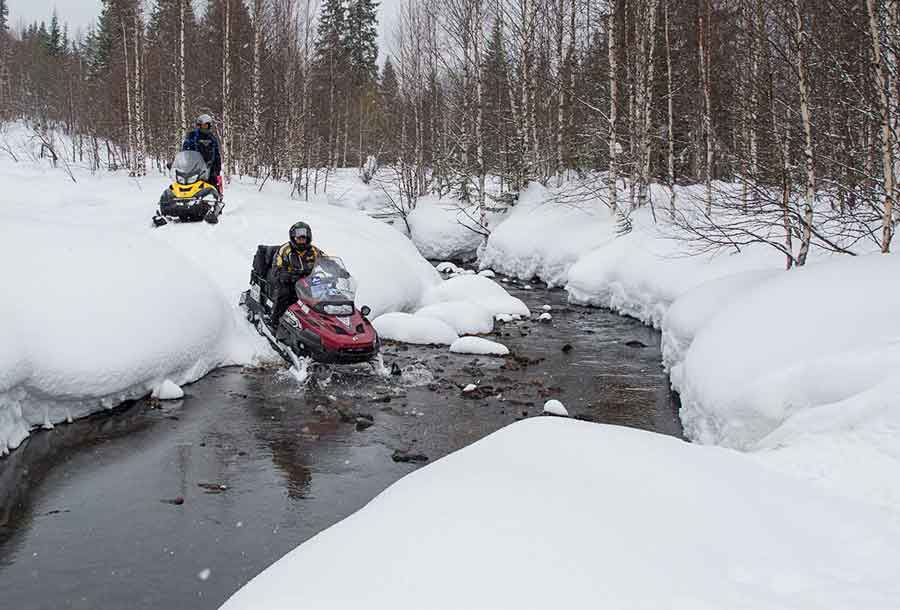 Snowmobile trip on Babinov Road in Urals over brook during adventure in Russia.