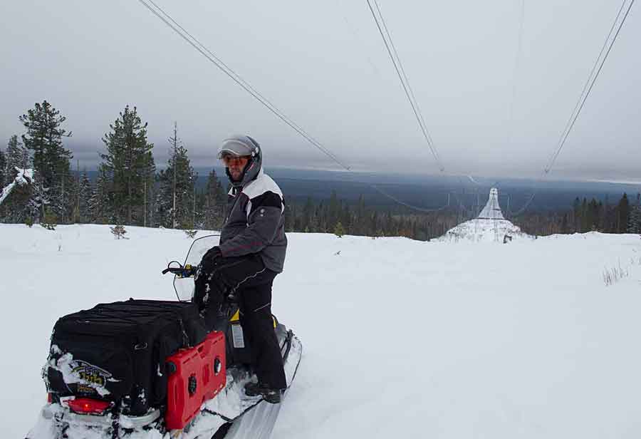 Evgeniy Borodin snowmobiling the continental boundary of Asia and Europe in Russia along power lines during snowmobile adventure.