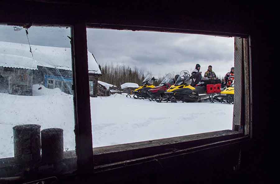 Snowmobilers on Lenin Street in the abandoned ghost town of Bolshaya, Russia.