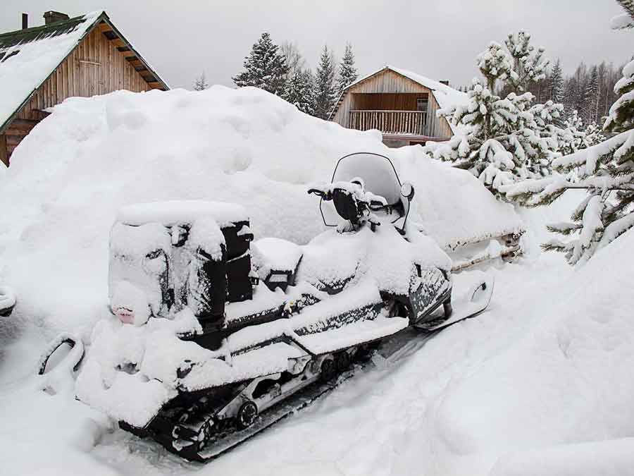 Snow covered snowmobile and cottage in Kytlym Russia