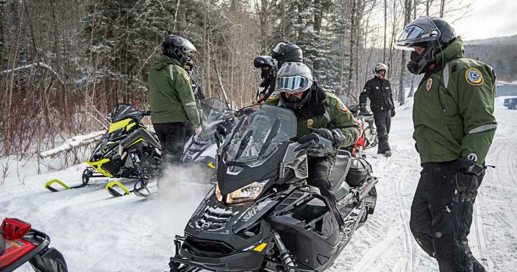NH Fish and Game officers on snowmobiles in Coos County.
